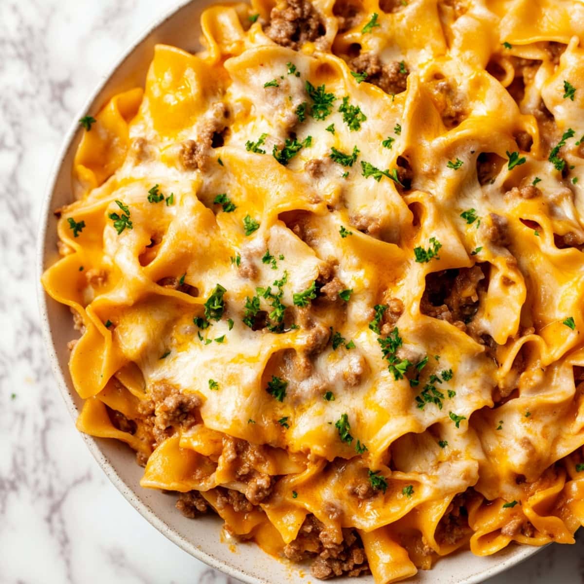 A serving of beef noodle casserole on a plate, garnished with chopped parsley.