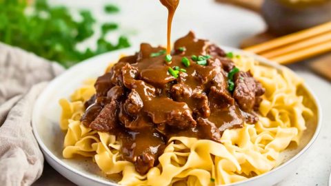 A serving of egg noodles with savory beef on top.