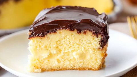 Boston cream pie poke cake slice served in a white plate.