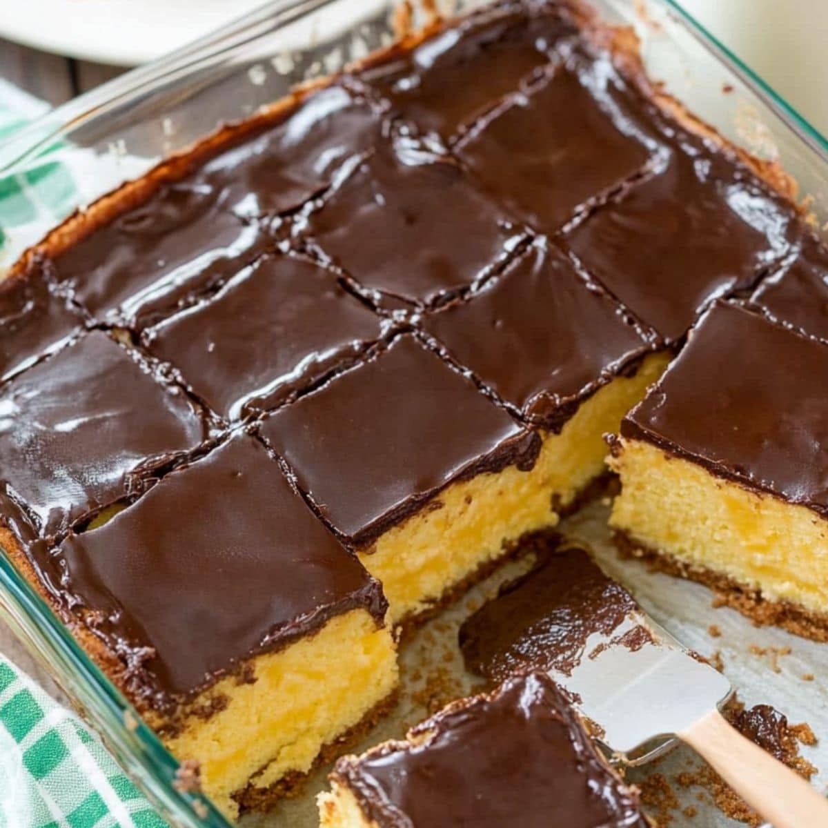 Sliced Boston cream pie poke cake in a glass baking dish, top view