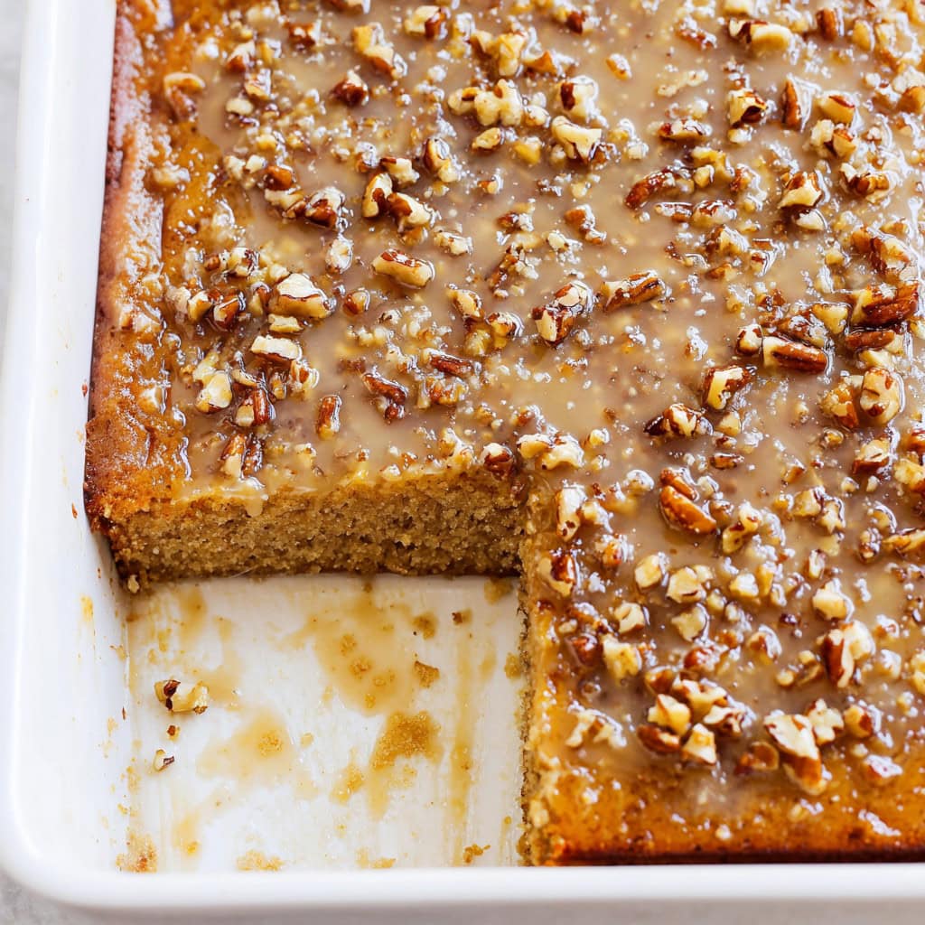 Butter pecan praline poke cake in a white baking dish.