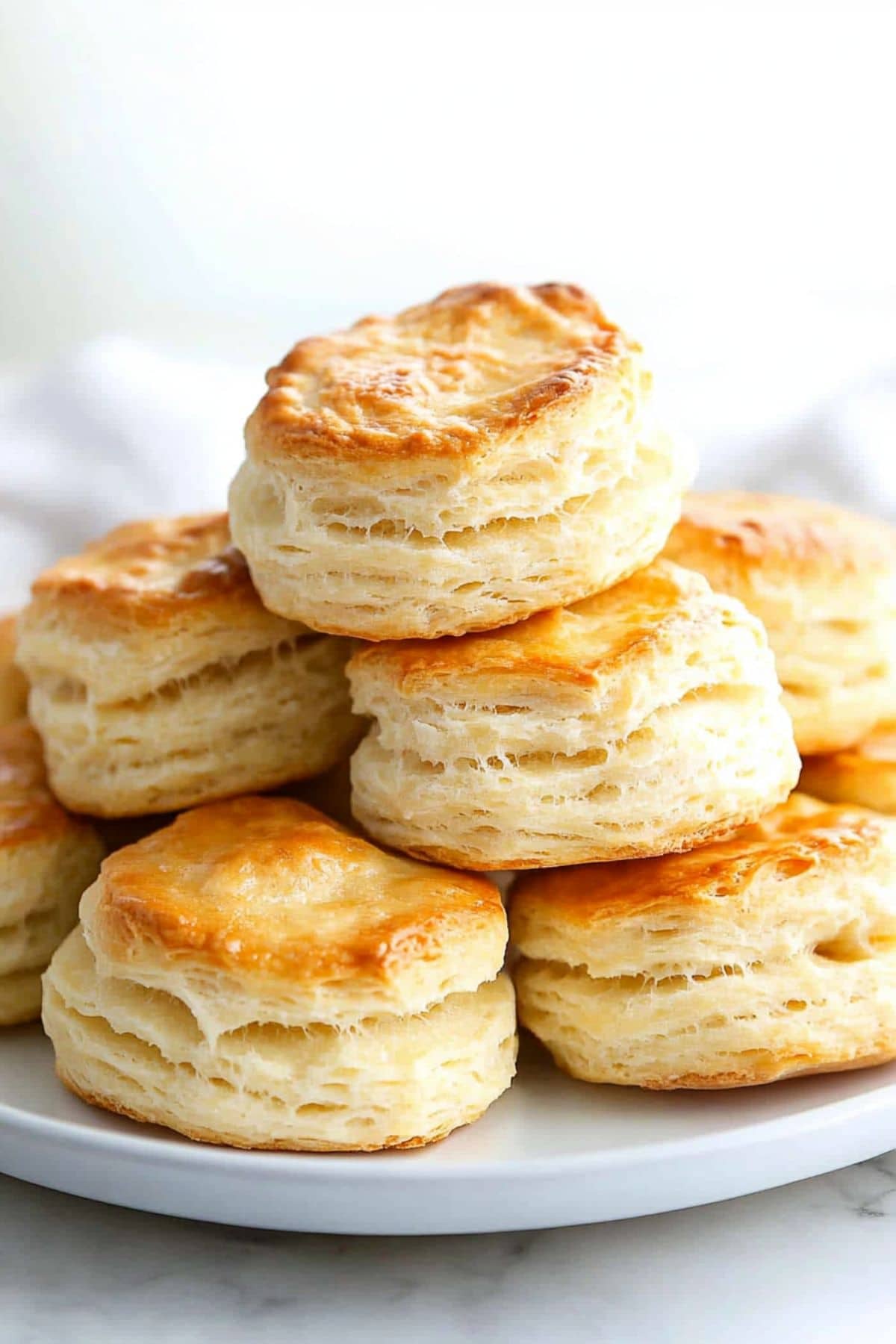 Bunch of buttermilk biscuits arranged on a white plate.