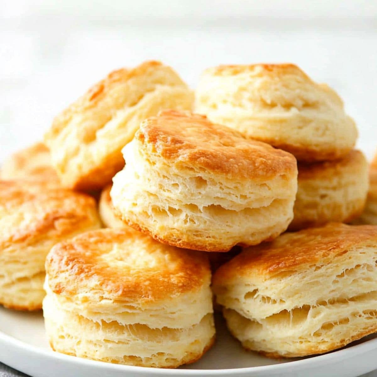 Buttermilk biscuits stacked on top of each other served on a white plate.