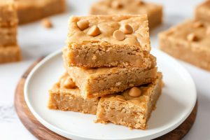 Butterscotch bars stacked on top of each other served on a white plate.