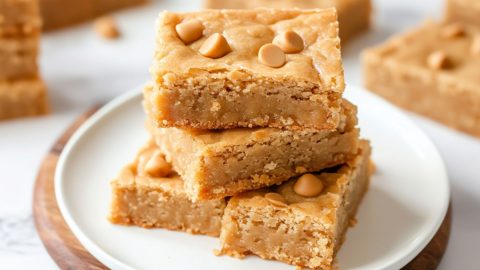 Butterscotch bars stacked on top of each other served on a white plate.