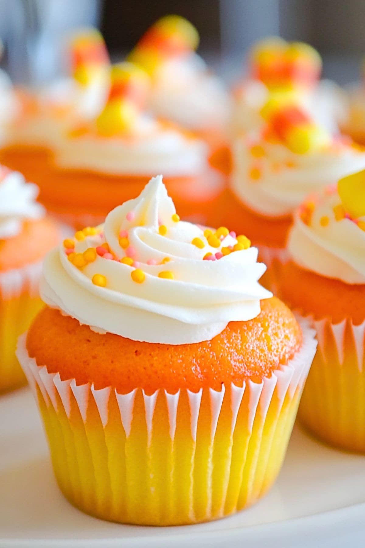 Orange and yellow cupcakes garnished with buttercream and candy sprinkles.