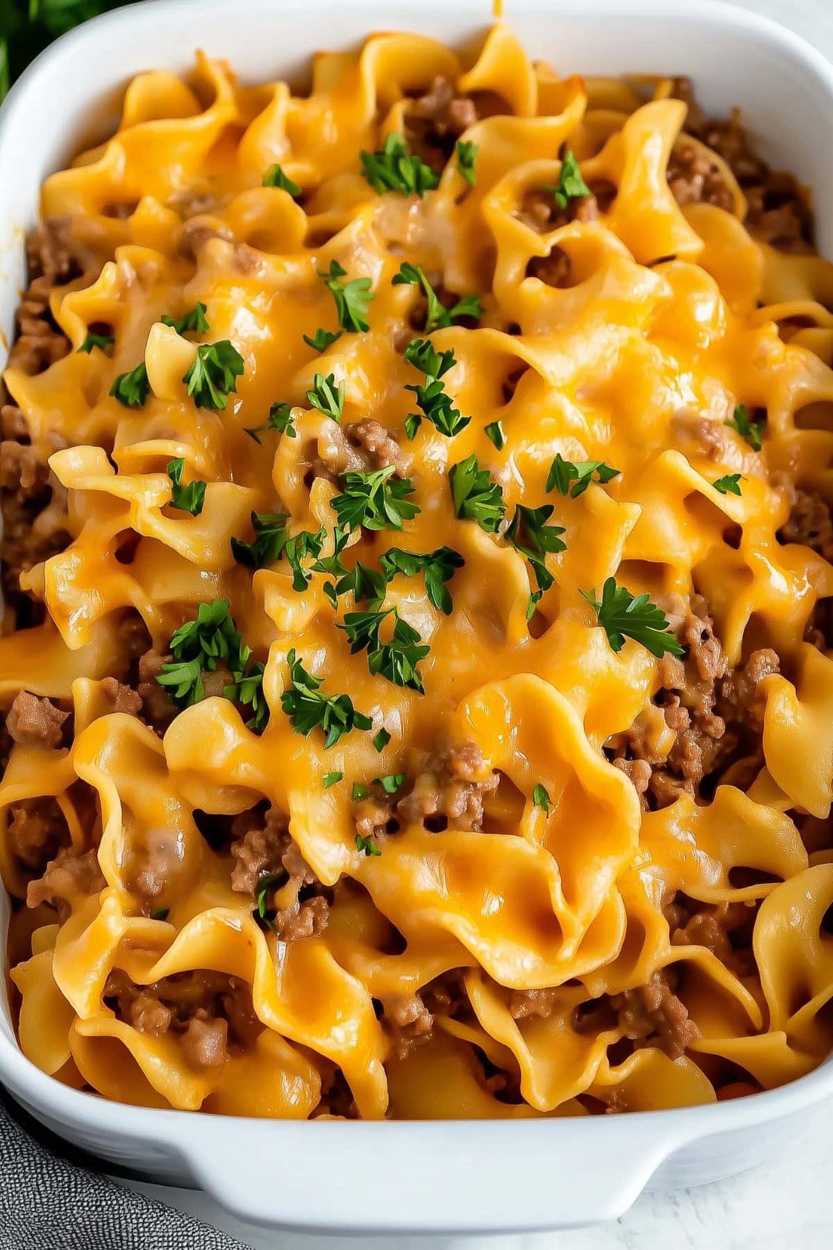 A baked beef noodle casserole with melted cheese on top, served in a baking dish.