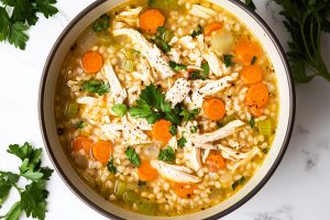 A vibrant bowl of chicken barley soup with colorful vegetables,