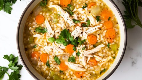 A vibrant bowl of chicken barley soup with colorful vegetables,