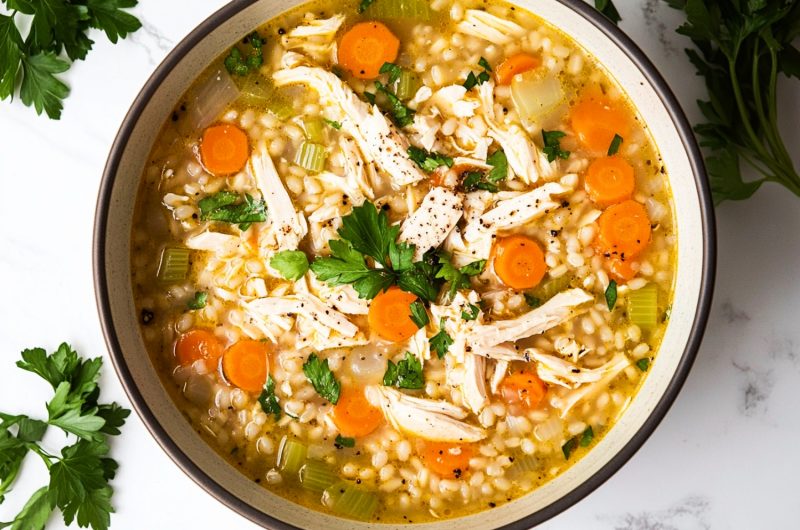 A vibrant bowl of chicken barley soup with colorful vegetables,