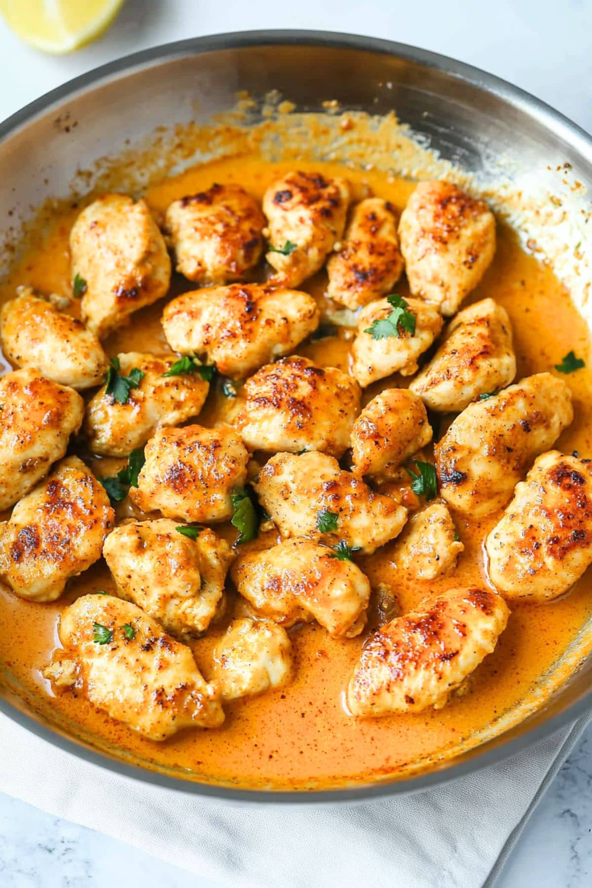 Chicken bites cooked in paprika infused sauce with heavy cream cooked in a skillet.