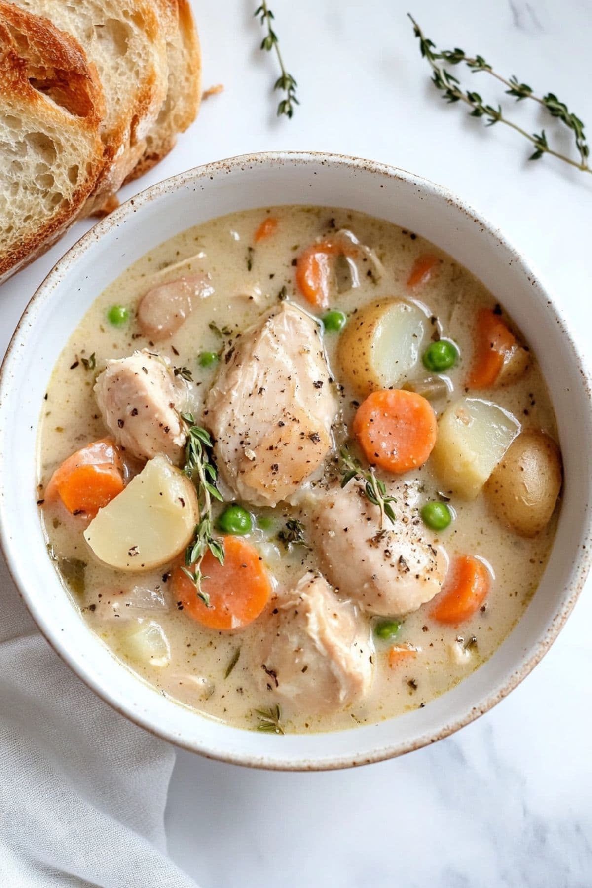 Top view of a serving of chicken stew with  sliced potatoes, carrots and green peas. 