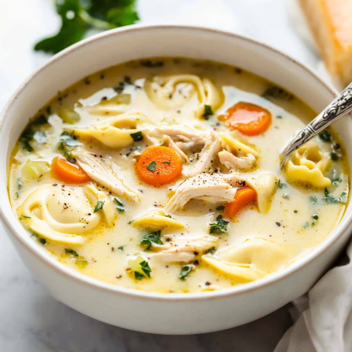 Chicken tortellini soup served on a white bowl.