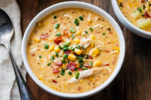 Creamy homemade chowder with vibrant yellow corn, juicy chicken pieces, and a sprinkling of green onions on top.