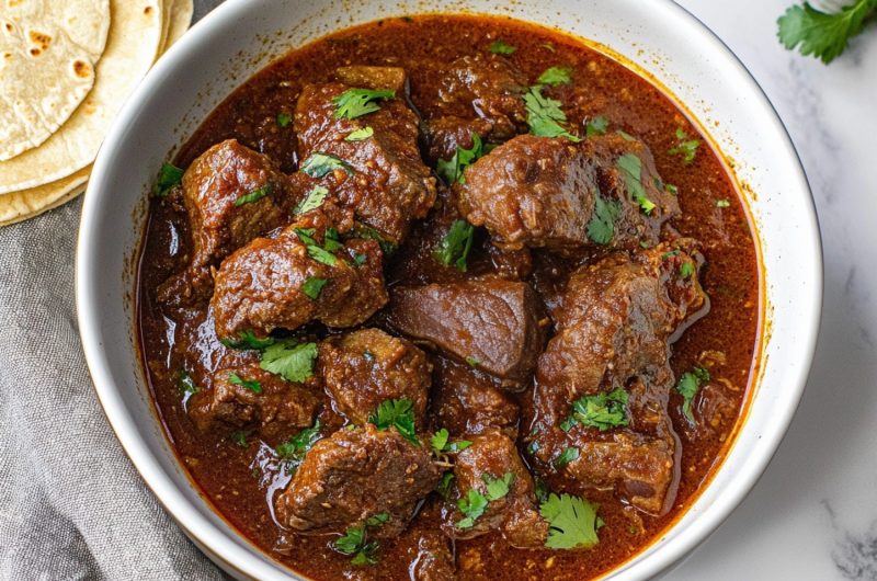An overhead shot of chili Colorado, showing a thick sauce made from dried chilies, smothering juicy beef chunks.