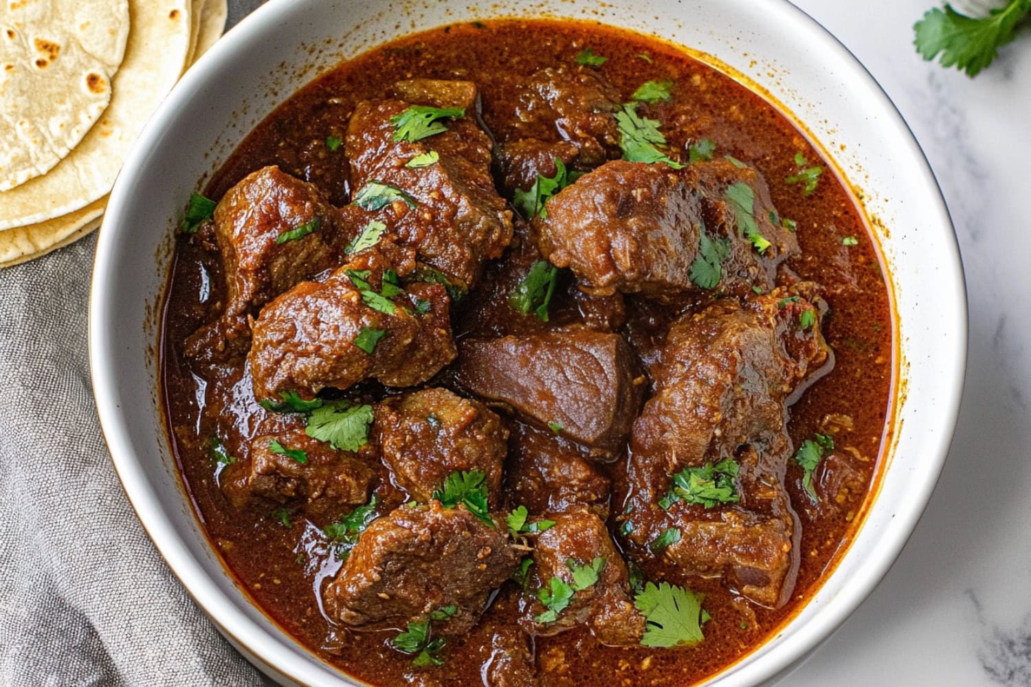 An overhead shot of chili Colorado, showing a thick sauce made from dried chilies, smothering juicy beef chunks.