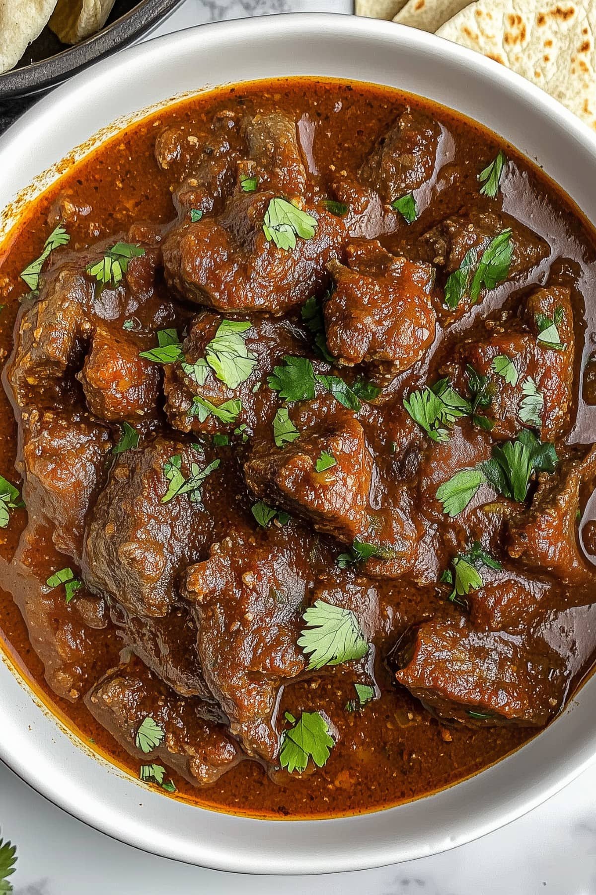 A plate of rich, red chili Colorado with tender beef chunks simmered in a deep, smoky red sauce.