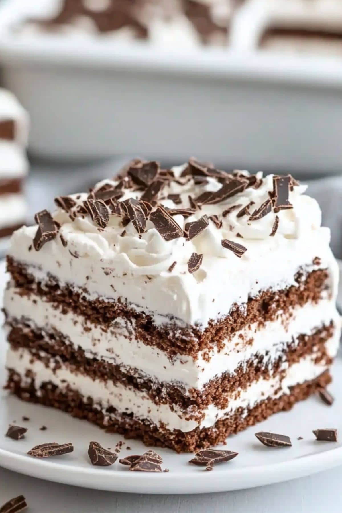 Square slice serving of chocolate icebox cake with chocolate crumbs toppings served in a white plate.