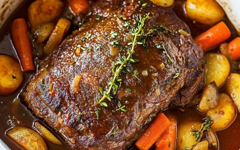 Roast chuck beef with potatoes and carrots in a Dutch oven pot.