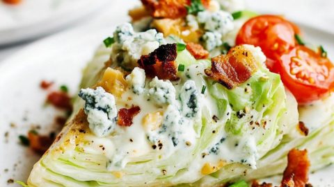 Classic wedge salad with blue cheese dressing, crumbled bacon, cherry tomato halves and crumbled blue cheese.