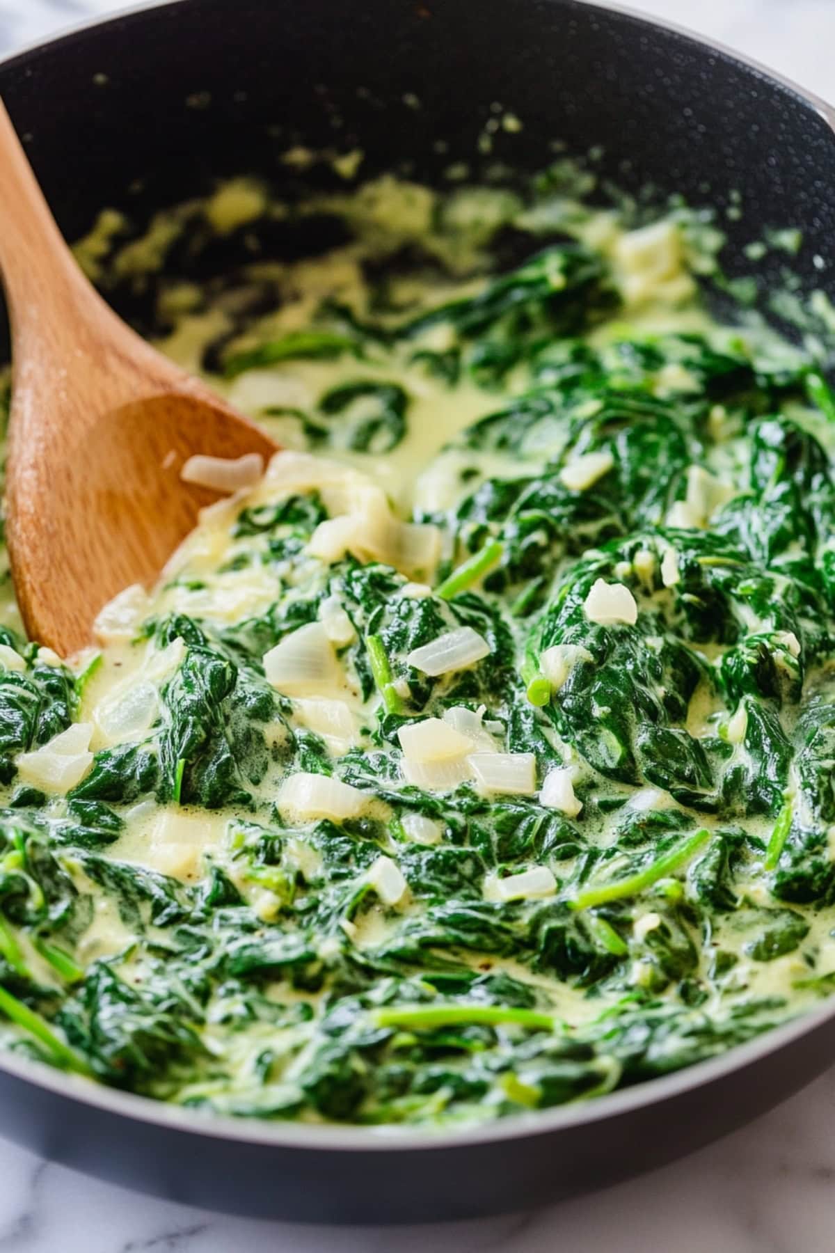 Rich and creamy spinach with onions and garlic in a skillet