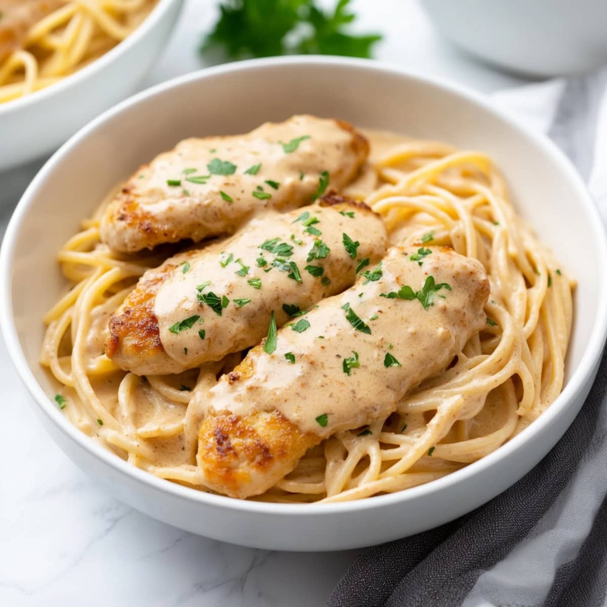 Creamy chicken Lazone with cajun sauce and pasta, garnished with parsley.