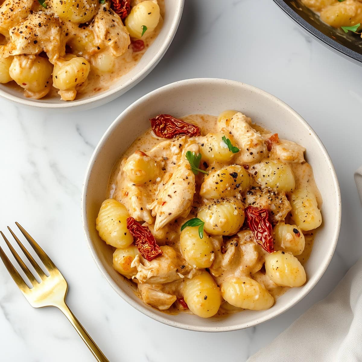 A comforting bowl of creamy chicken and gnocchi with sun-dried tomatoes and green chopped parsley.