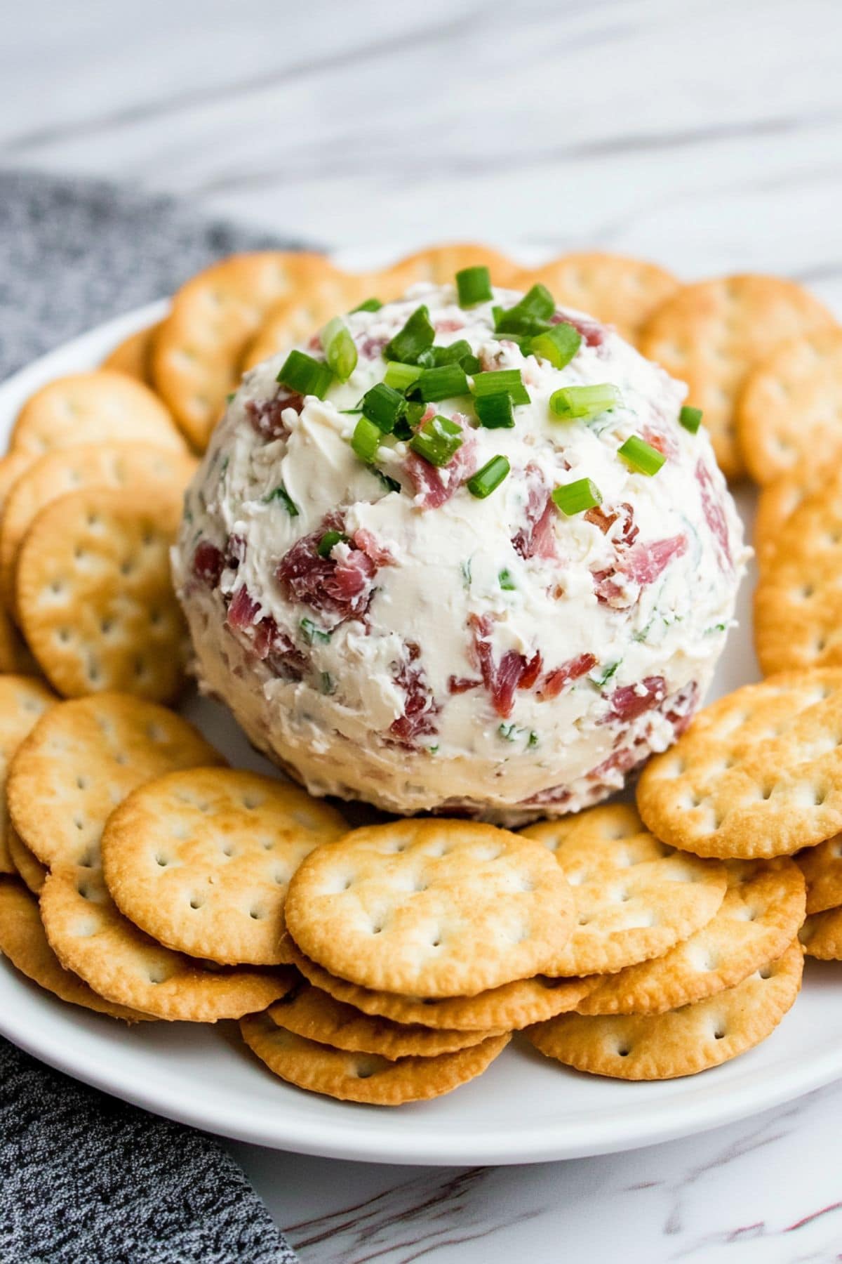 Dried beef cheese roll in the middle of crackers served on a white plate garnished with chopped parsley.