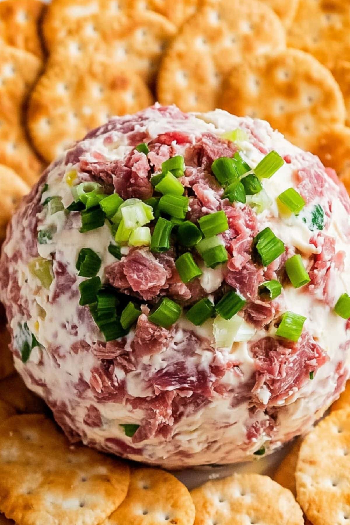 Dried beef cheese ball garnished with chopped onions served with crackers.