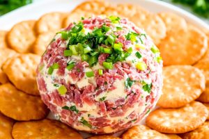 Cream cheese ball mixed with chopped dried beef and chopped onions served with a platter of crackers.