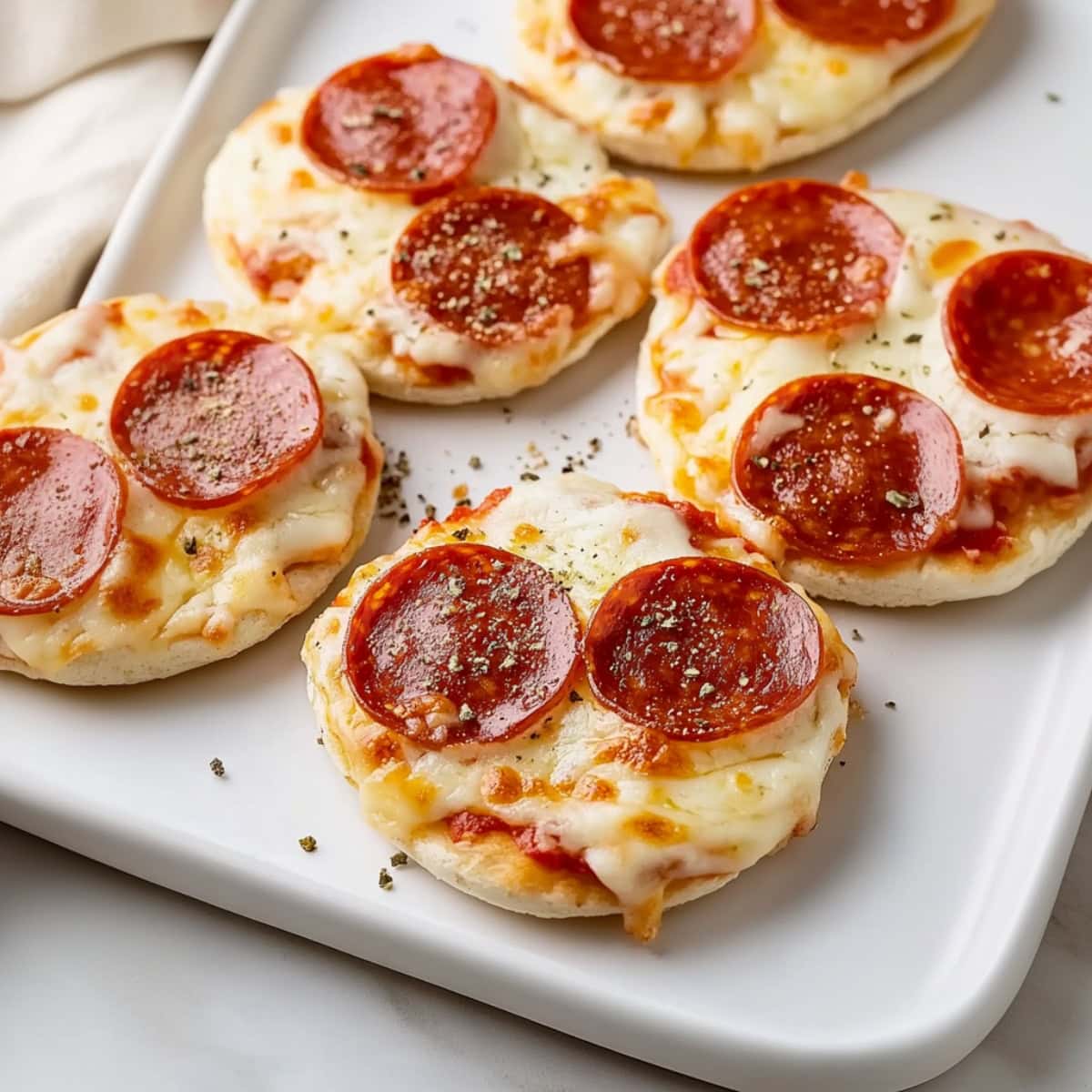 English muffin pizzas in a white platter.