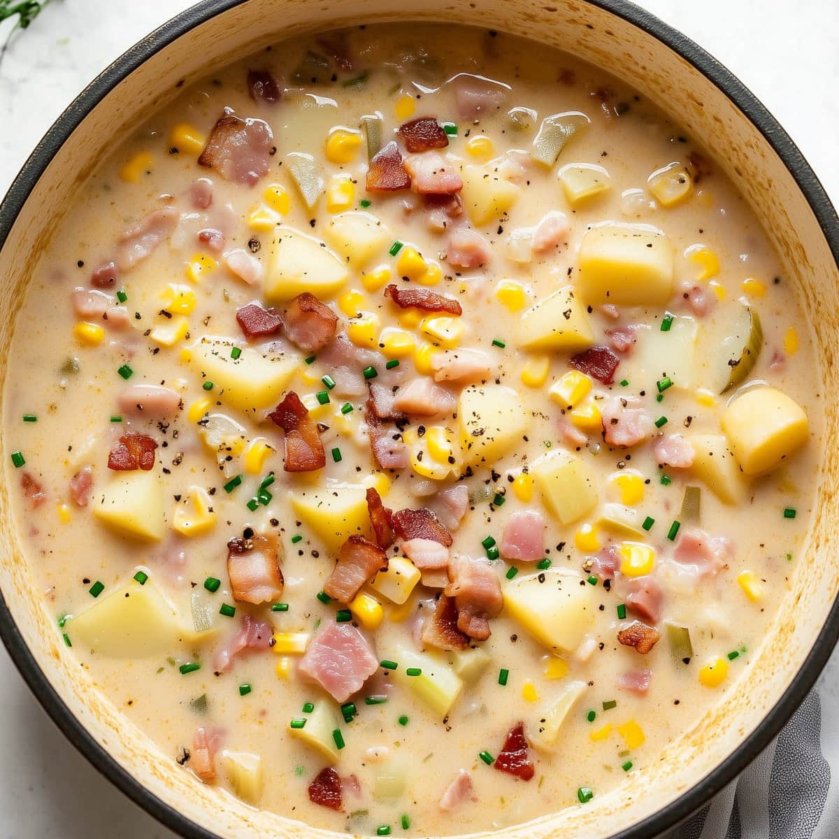 A large pot of corn chowder with meat and vegetables.