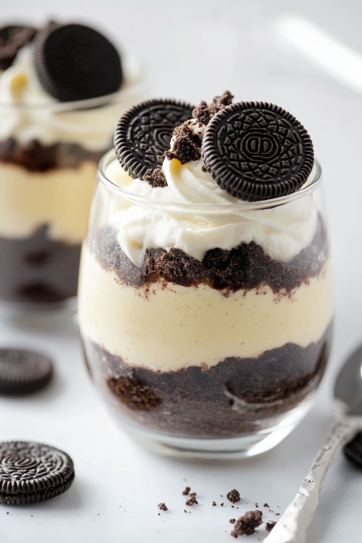 Oreo pudding assembled in glasses garnished with whipped cream and cookies.