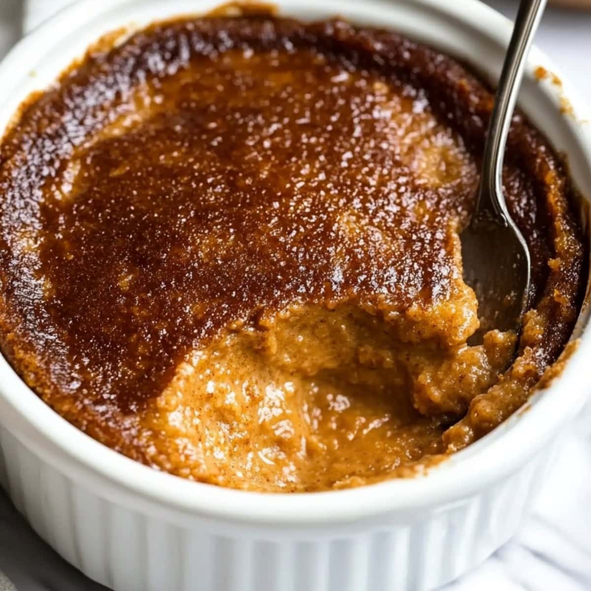 A close-up shot of Indian pudding served in a ramekin bowl.