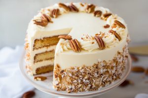 A single slice of Italian Cream Cake showing moist, flavorful layers and a thick layer of frosting topped with pecans and coconut.