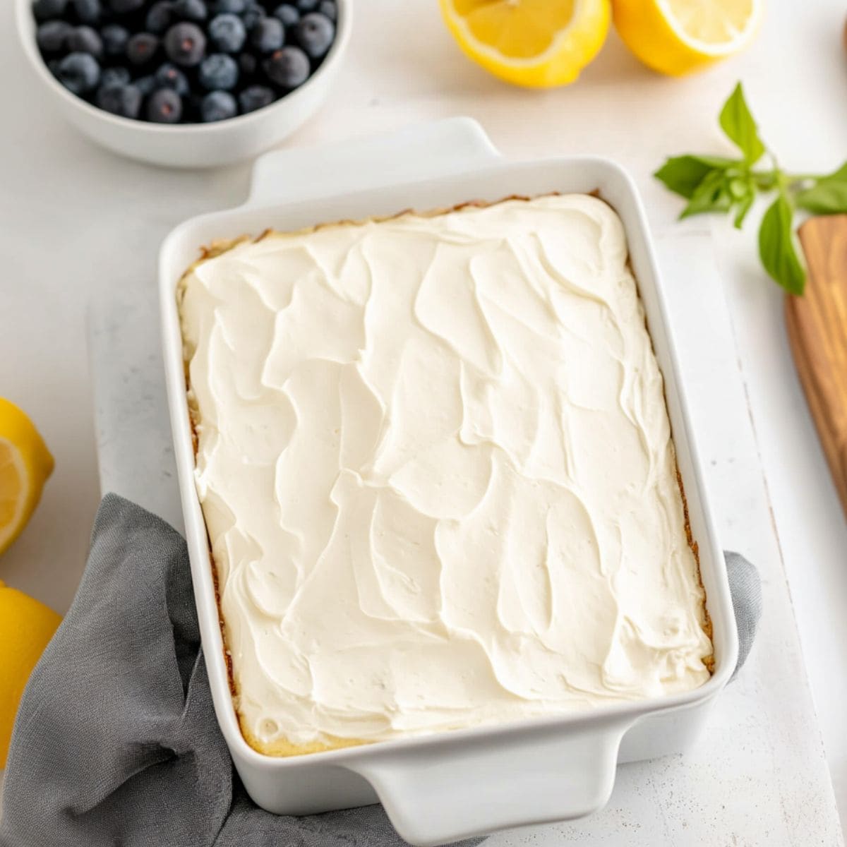 Cream cheese frosting covered lemon cake in a baking dish.