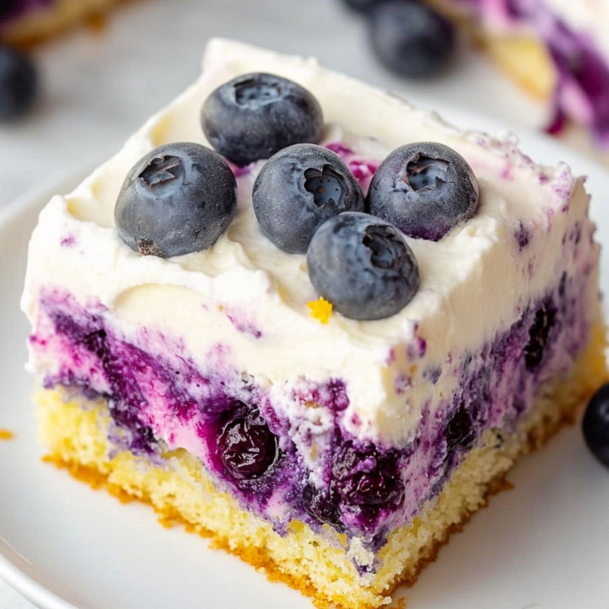 Square slice of lemon blueberry cake garnished with blueberries