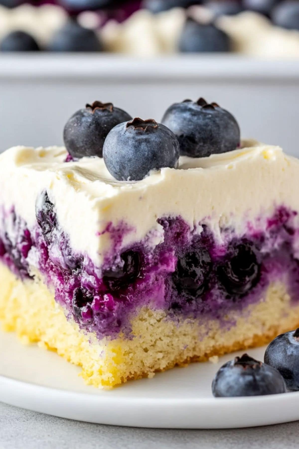 A slice of lemon blueberry poke cake served in a white plate.