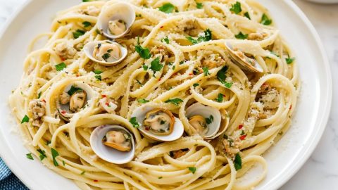 A plate of linguine topped with tender clams and a light, garlicky white wine sauce, garnished with fresh parsley.