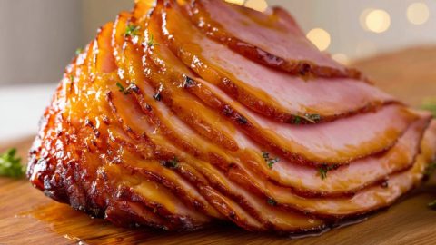 Maple glazed ham in a wooden cutting board.