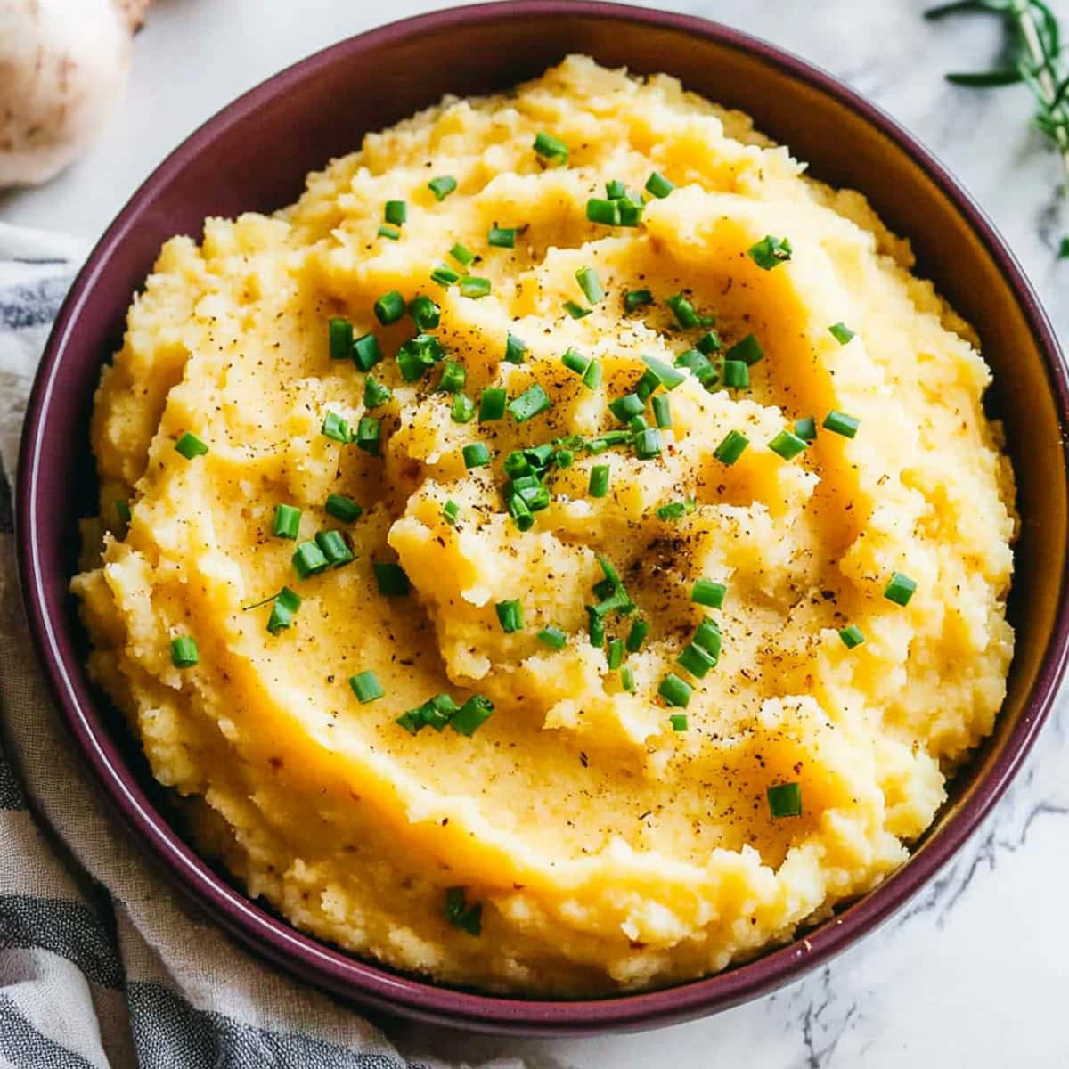 Creamy mashed swede with a rich, buttery texture, served in a brown bowl and topped with chopped chives