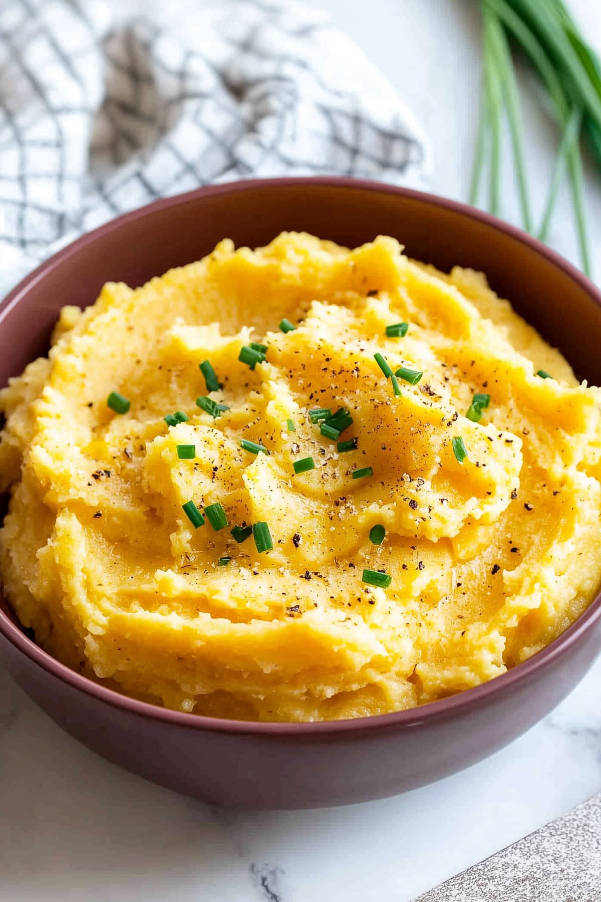 Mashed rutabaga with chopped chives and salt and pepper, in a bowl, close up