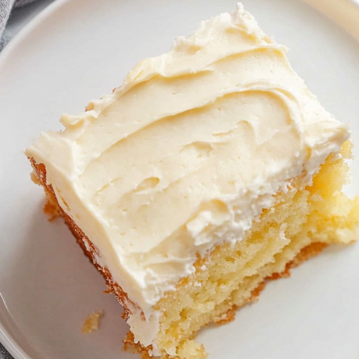 Square slice of moist pineapple cake with cream cheese frosting, top view