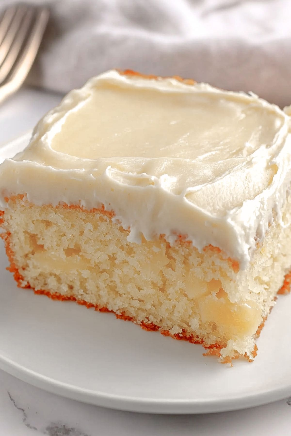 Square slice of Mexican Wedding cake with cream cheese frosting on a plate