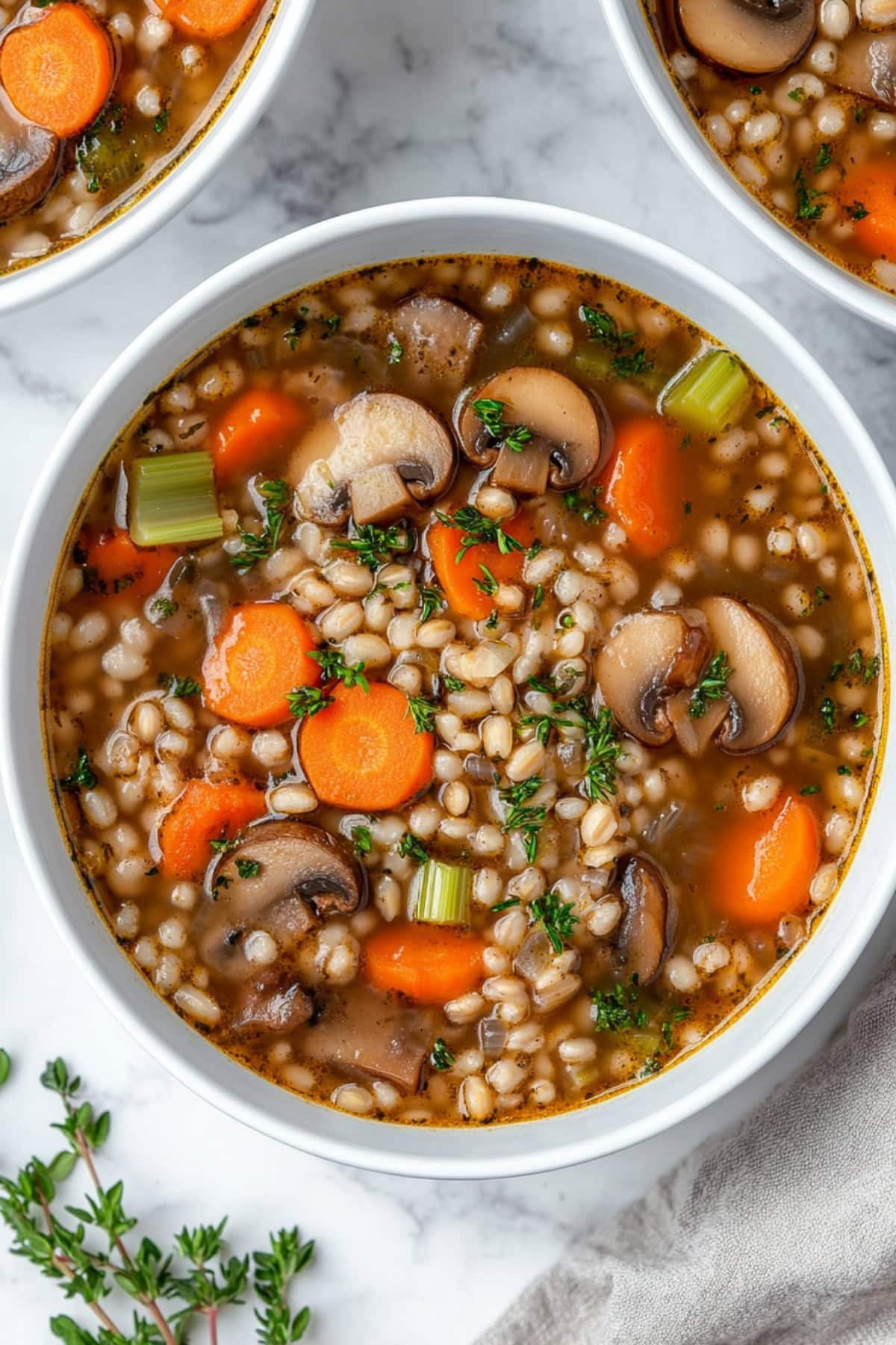 Homemade mushroom barley soup, served hot with a drizzle of olive oil and a sprinkle of black pepper.