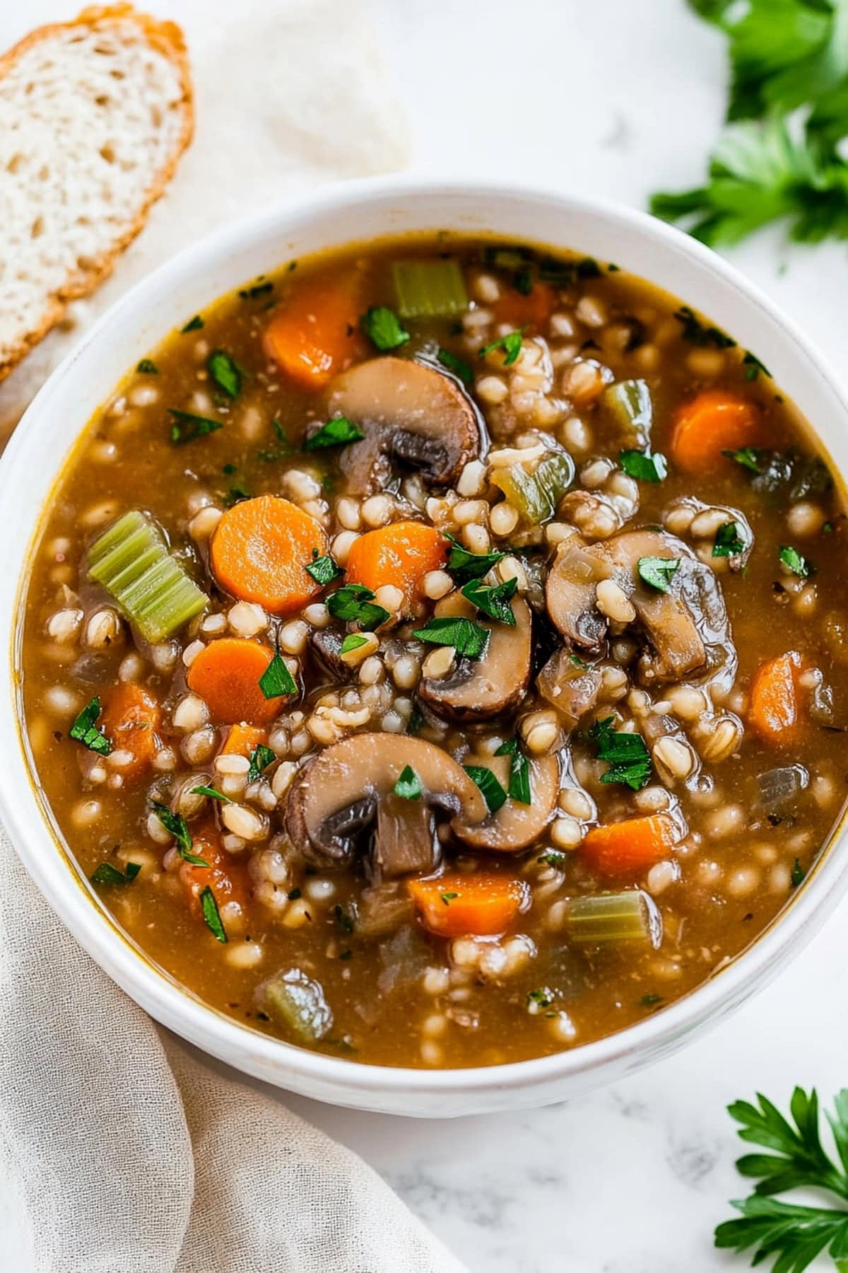 A comforting bowl of mushroom barley soup, with diced carrots, and celery.