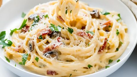 Cream pasta carbonara mushroom served on a white plate.