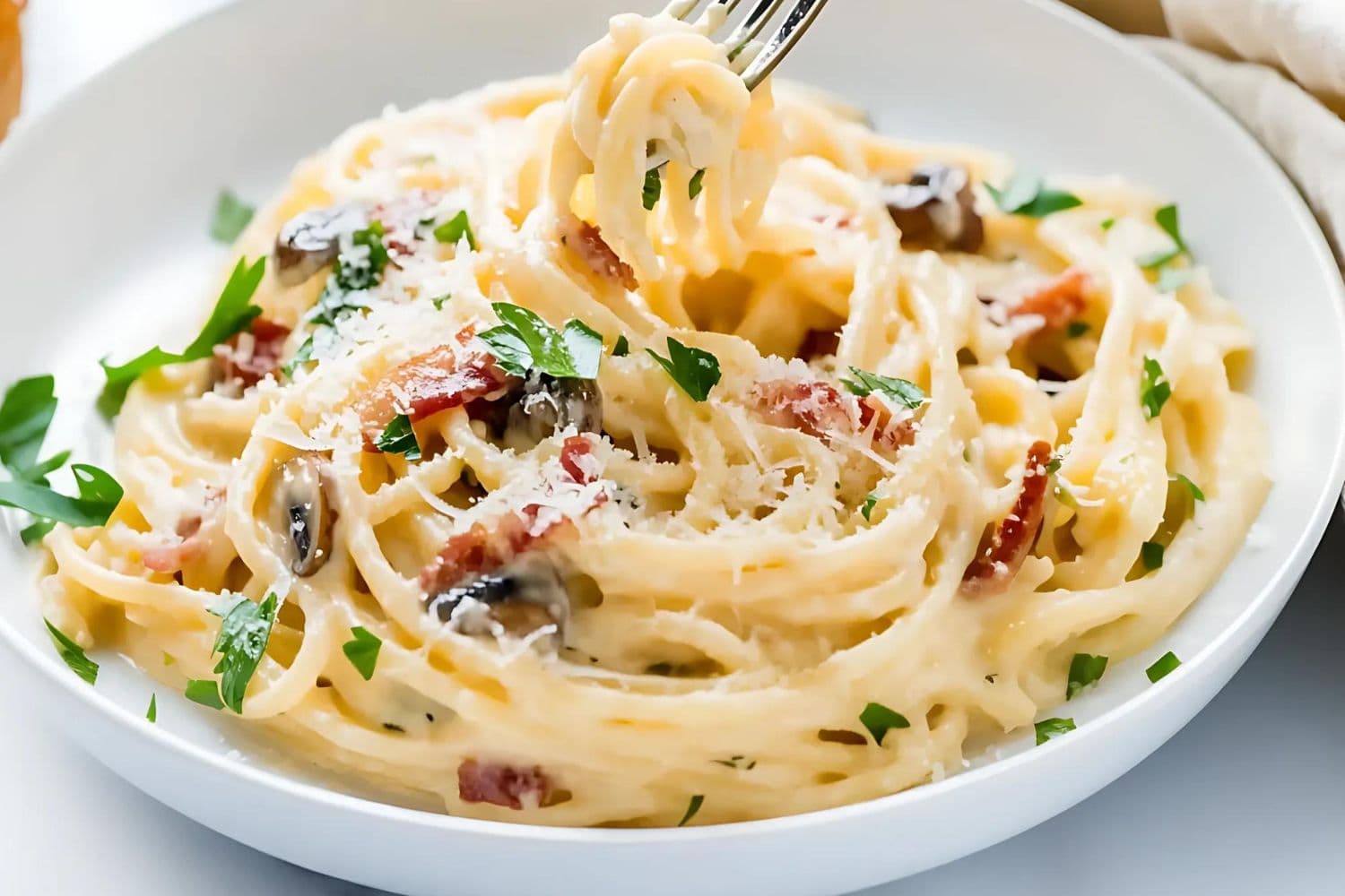 Cream pasta carbonara mushroom served on a white plate.