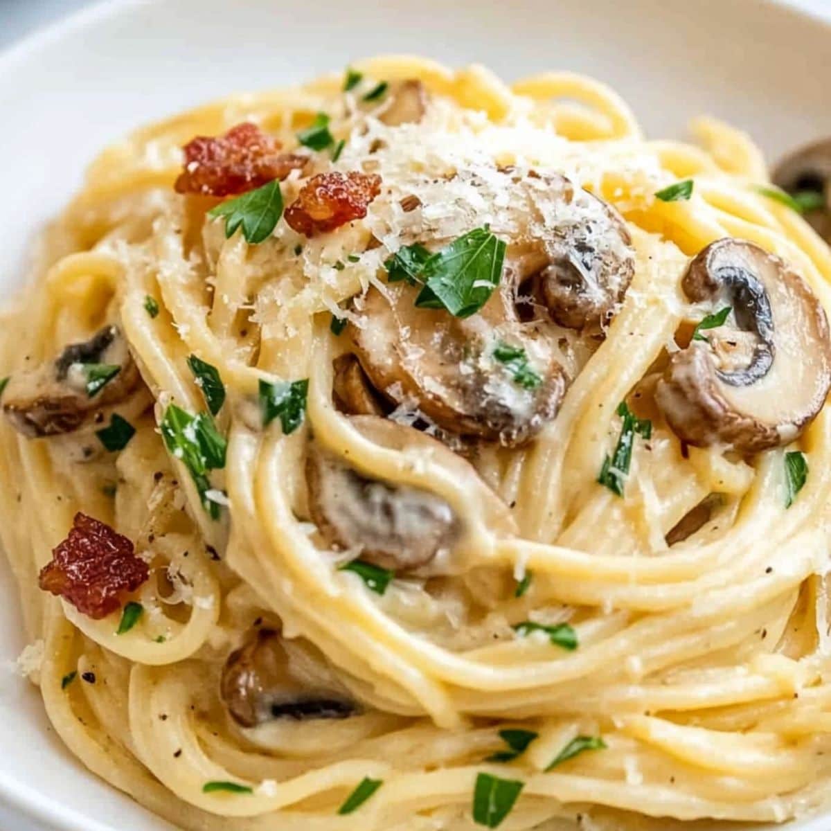 Pasta carbonara with mushroom and chopped bacons garnished with chopped parsley.