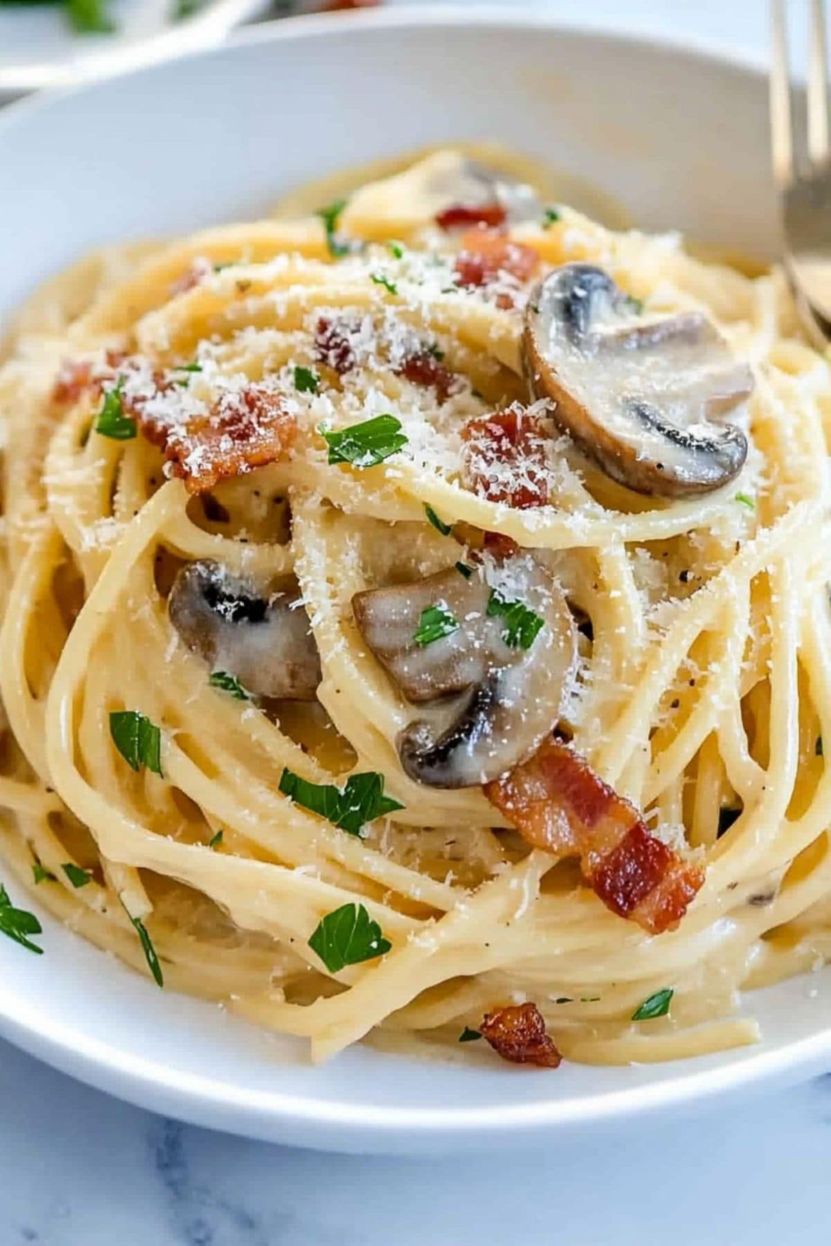 Serving of mushroom carbonara sprinkled with parmesan cheese on top.